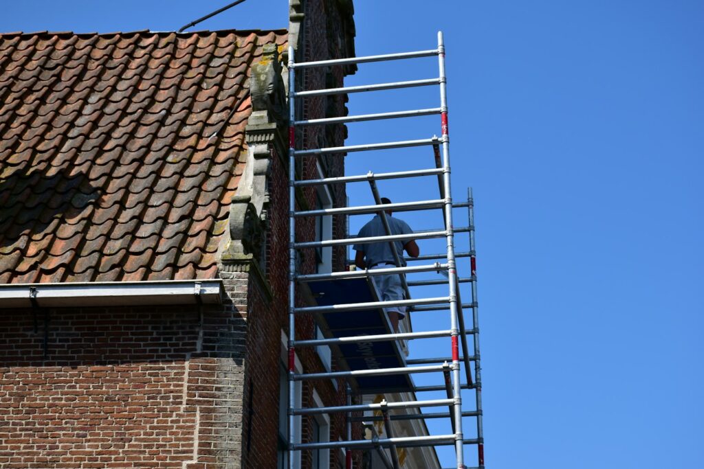 Arbeiter auf einem Gerüst an einer Hauswand beim Fassade streichen
