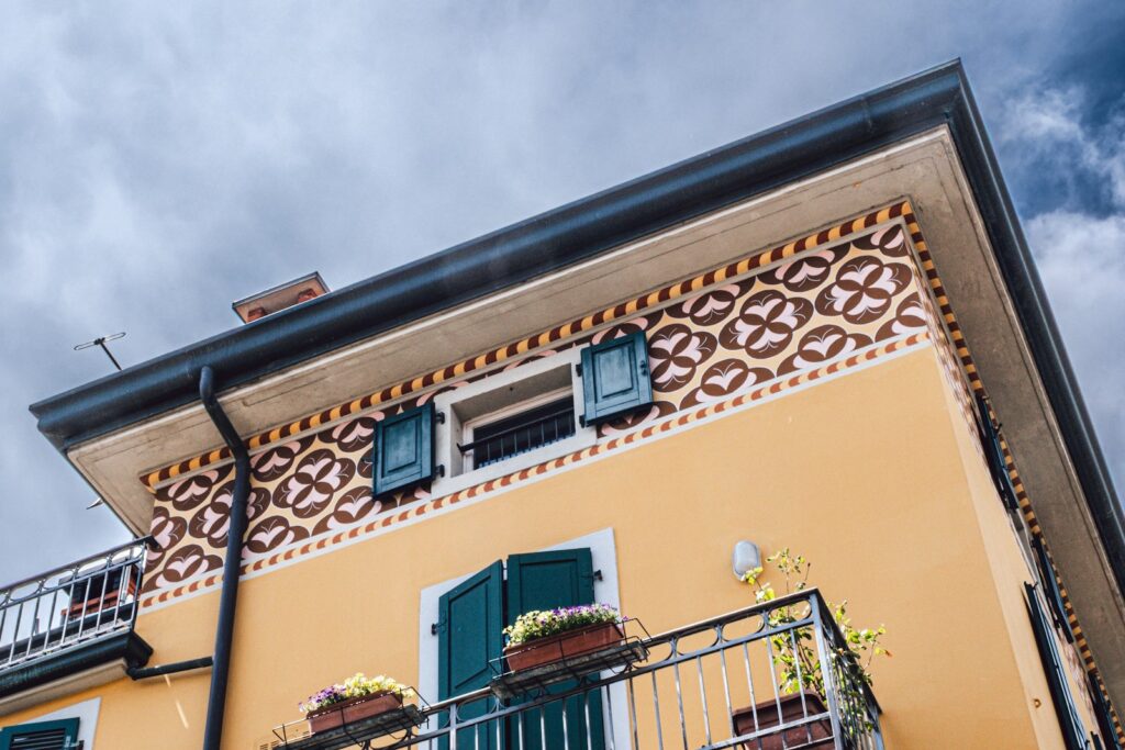 Gelbe Hausfassade mit blauen Fensterläden nach dem Fassade streichen