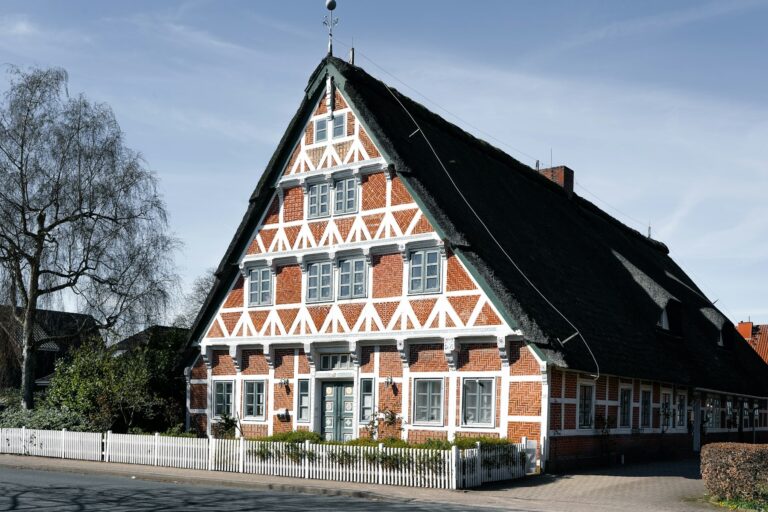 Immobilie bewerten: traditionelles Fachwerkhaus mit steilem Dach und weißem Zaun