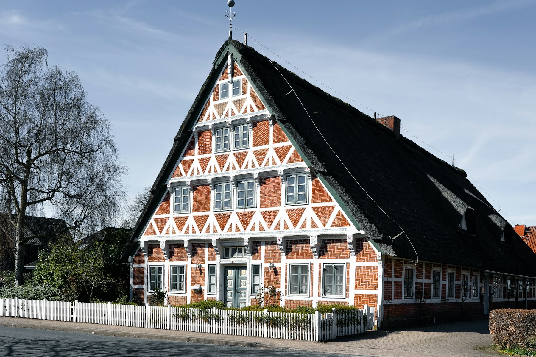 Immobilie bewerten: traditionelles Fachwerkhaus mit steilem Dach und weißem Zaun