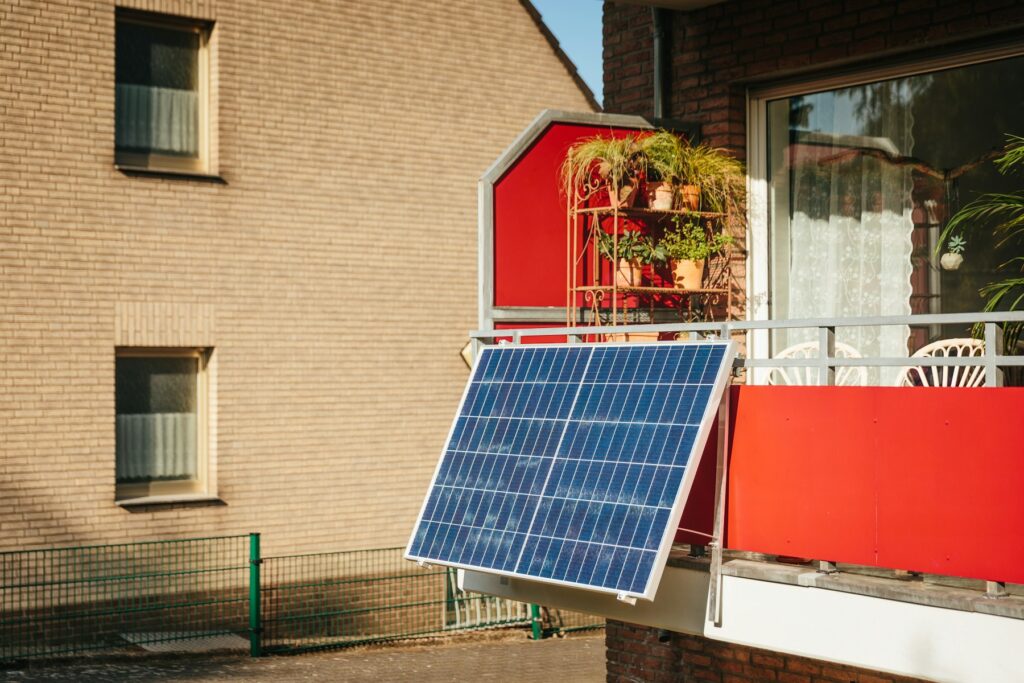 Balkonkraftwerk mit Solarmodul an einem Balkon mit Pflanzen – vor dem Betrieb musst du das Balkonkraftwerk anmelden