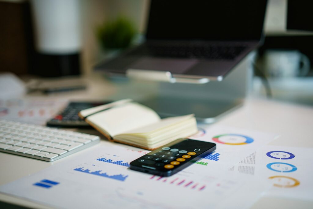 Bauzinsen Prognose 2027: Schreibtisch mit Smartphone und Finanzcharts