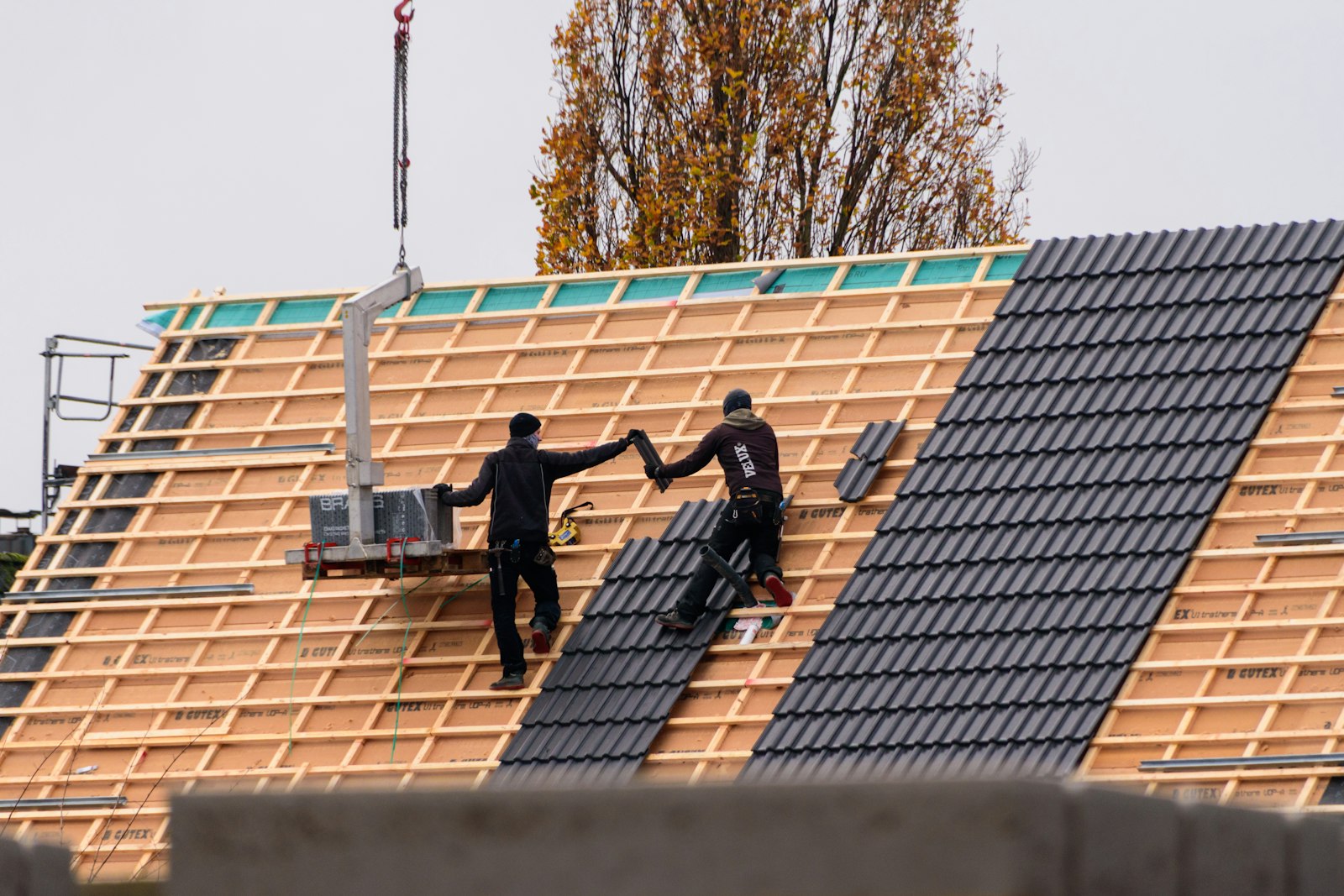Dachsanierung steuerlich absetzen: Handwerker decken ein Dach mit neuen Ziegeln