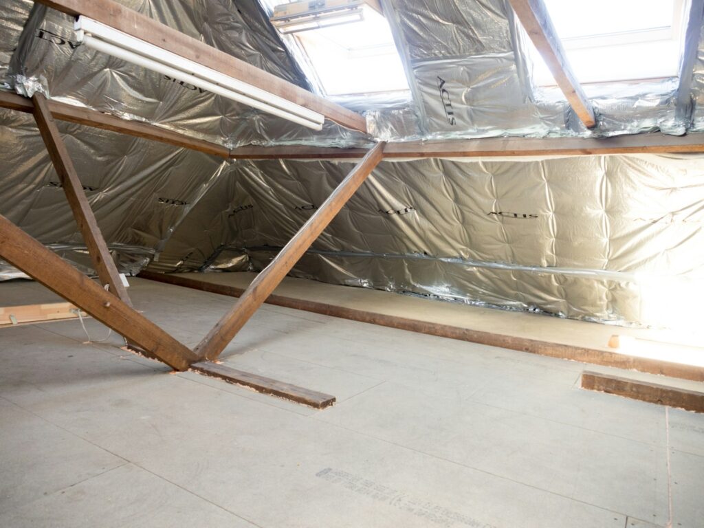 Förderung Sanierung: gedämmter Dachboden mit Holzbalken und Dachfenstern