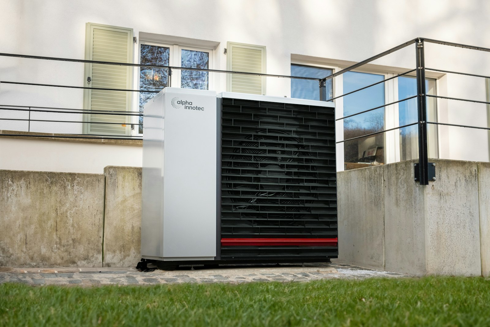 Gasheizung auf Wärmepumpe umrüsten: weiße Außeneinheit einer Wärmepumpe vor einem Wohnhaus