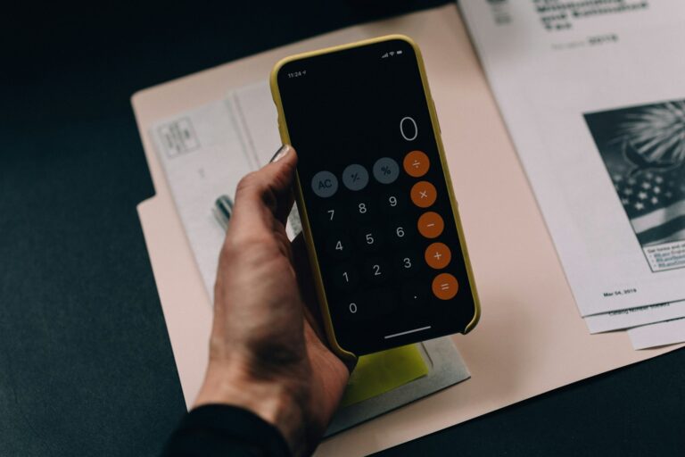 Grundsteuer verfassungswidrig: Hand hält Smartphone mit Taschenrechner über Steuerunterlagen