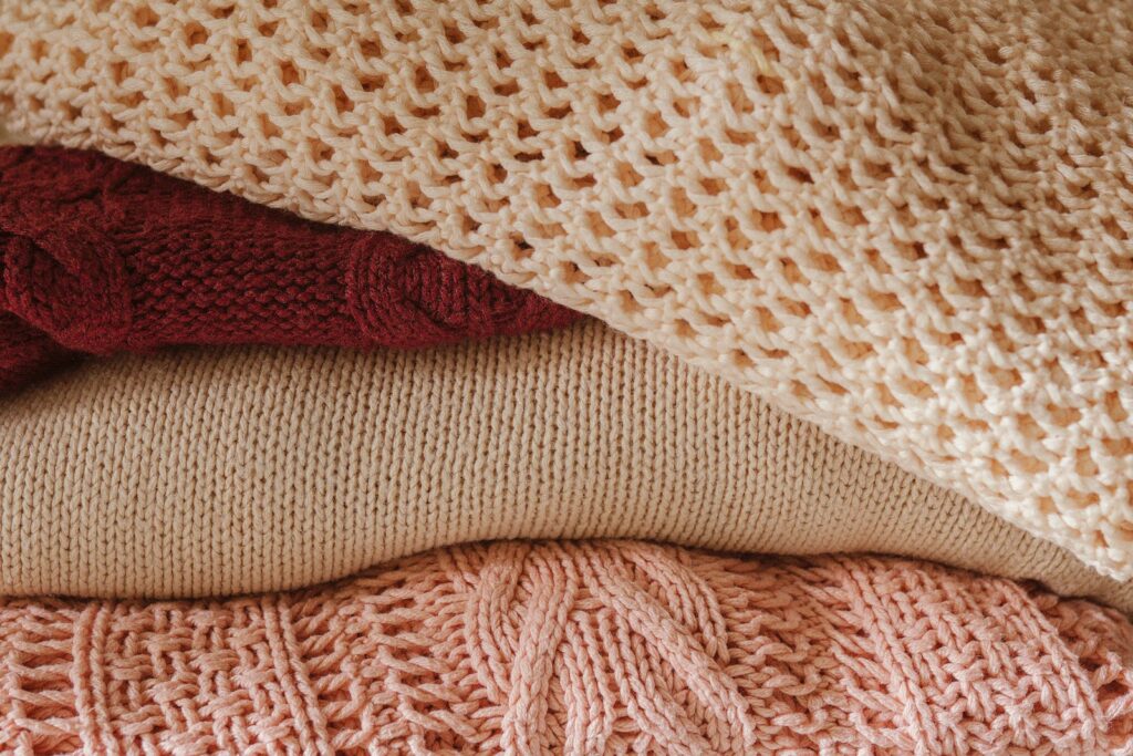 Motten im Kleiderschrank: Stapel aus Strickpullovern aus Wolle
