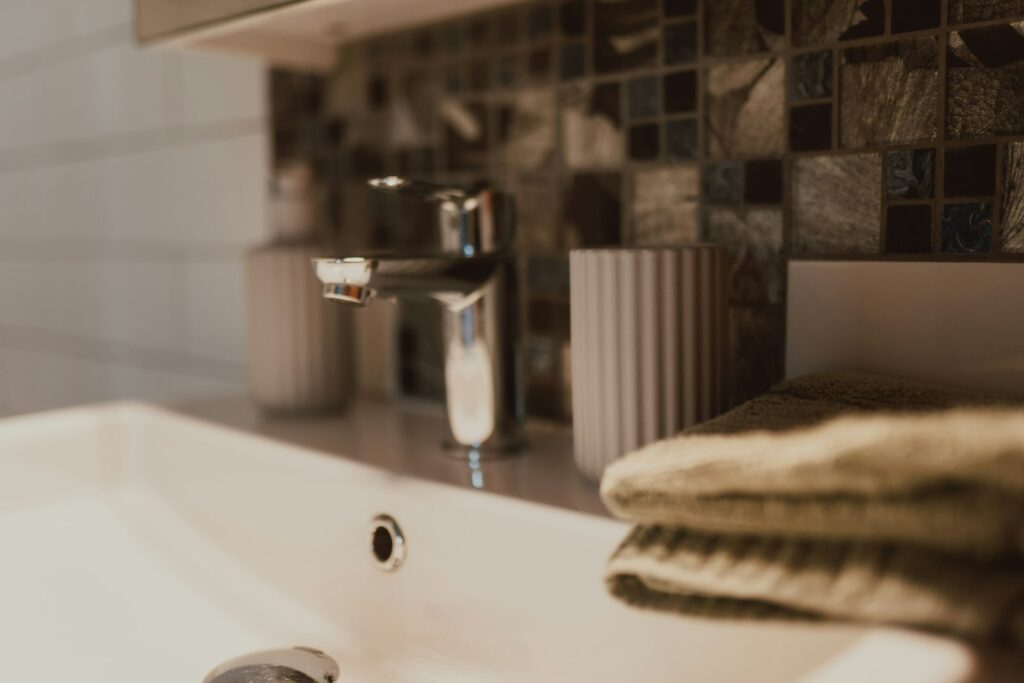 Silberfische Ursache – Badezimmer mit Waschbecken, Handtüchern und Mosaikfliesen