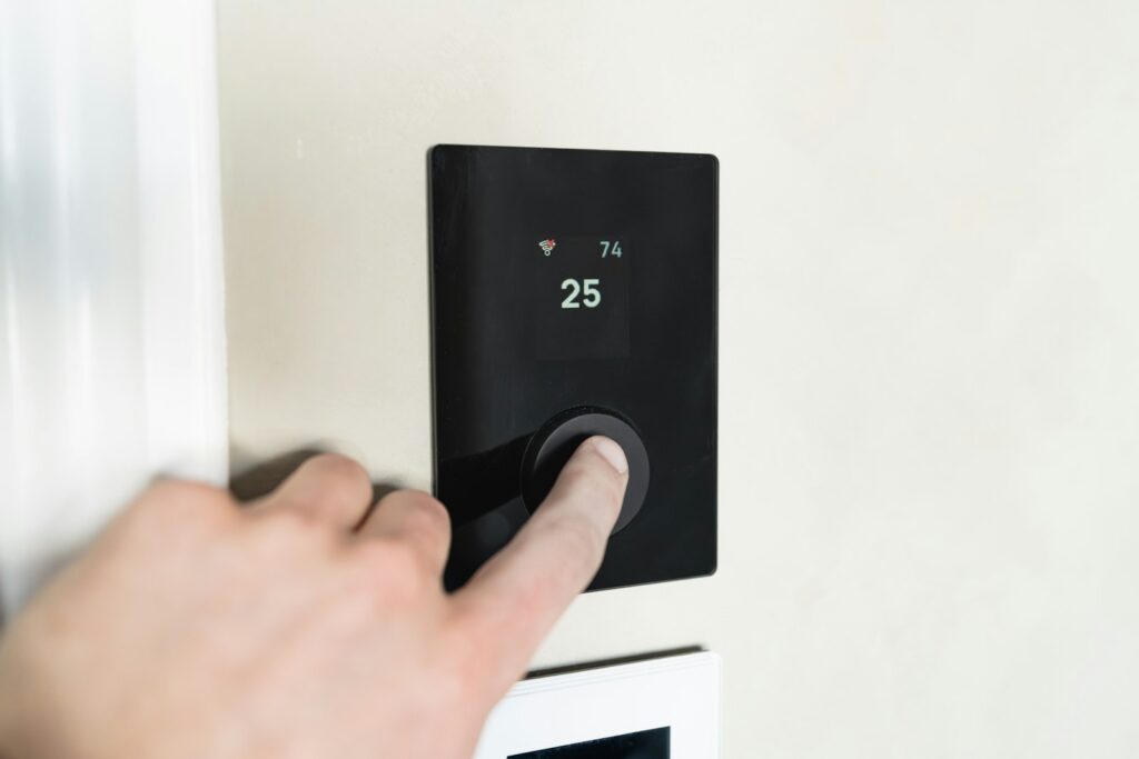 Smarte Thermostate: Finger drückt eine Taste am digitalen Thermostat-Display