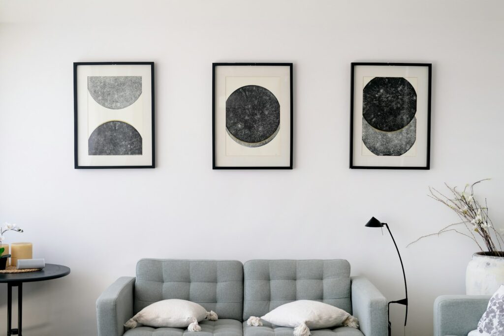 Wandgestaltung hinter Couch mit drei abstrakten Bildern über grauem Sofa